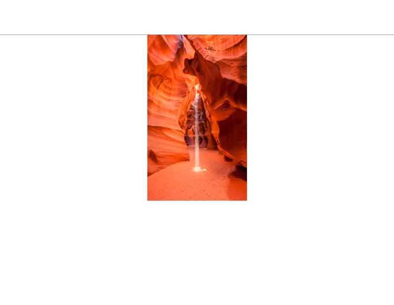 Die strahlende Lichtsäule im Antelope Canyon, einem Slot-Canyon in Arizona, USA, umgeben von rot gefärbten Felswänden.
