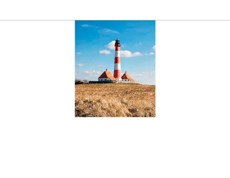 Roter und weißer Leuchtturm steht auf einer Wiese unter blauem Himmel mit einigen Wolken