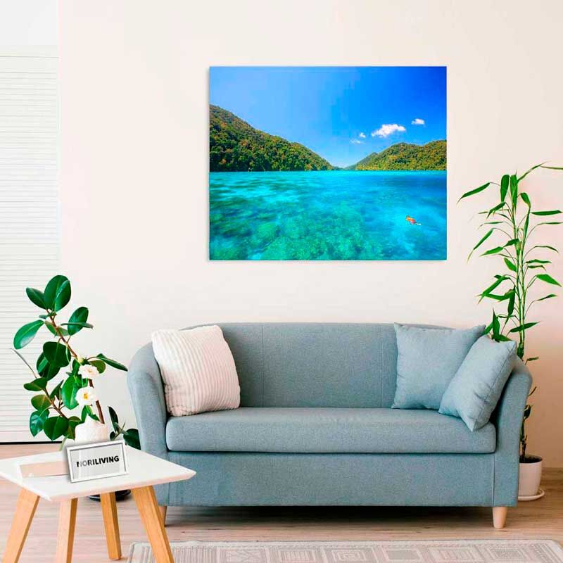 Wohnzimmer mit grauem Sofa, dekorativem Tisch und Leinwandbild eines tropischen Strandes an der Wand