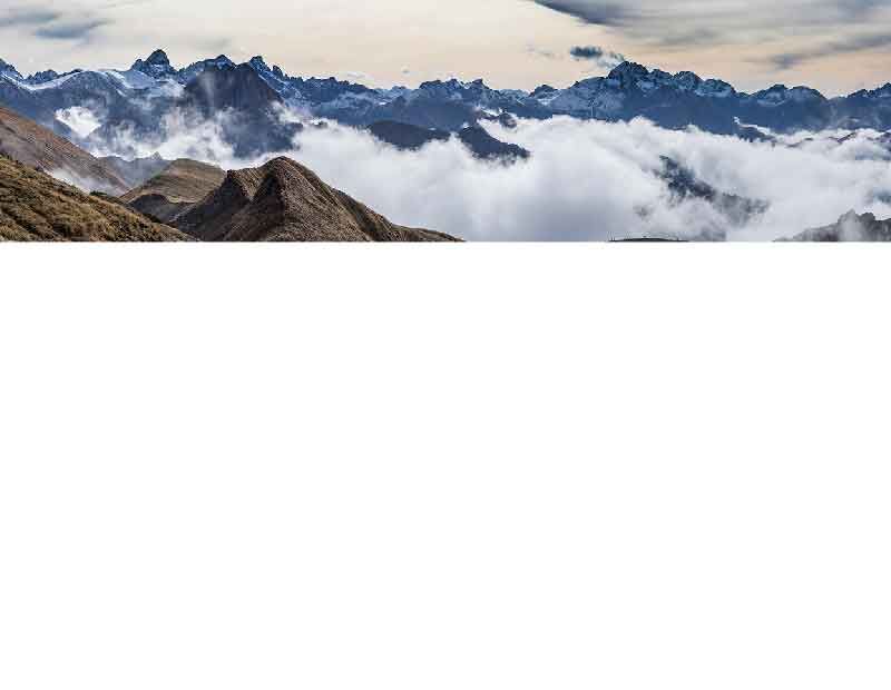 Eine malerische Berglandschaft mit Wolken, die um die schneebedeckten Gipfel schweben, bietet einen atemberaubenden Anblick.