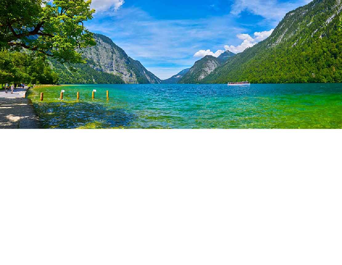 Blick auf den klaren, türkisblauen Königssee, umgeben von majestätischen Bergen und grünen Wäldern in Bayern, Deutschland