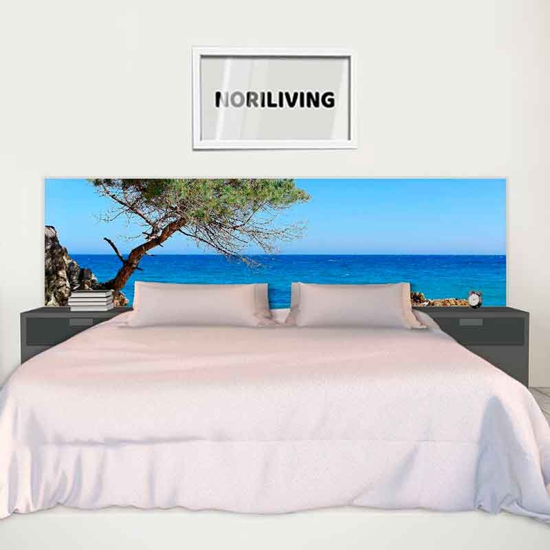 Modernes Doppelbett mit maritimer Kopfteilgestaltung, das einen Strand mit blauem Meer zeigt, flankiert von Nachttischen und Bücherstapeln, unter einem 'Noriliving'-Bilderrahmen.