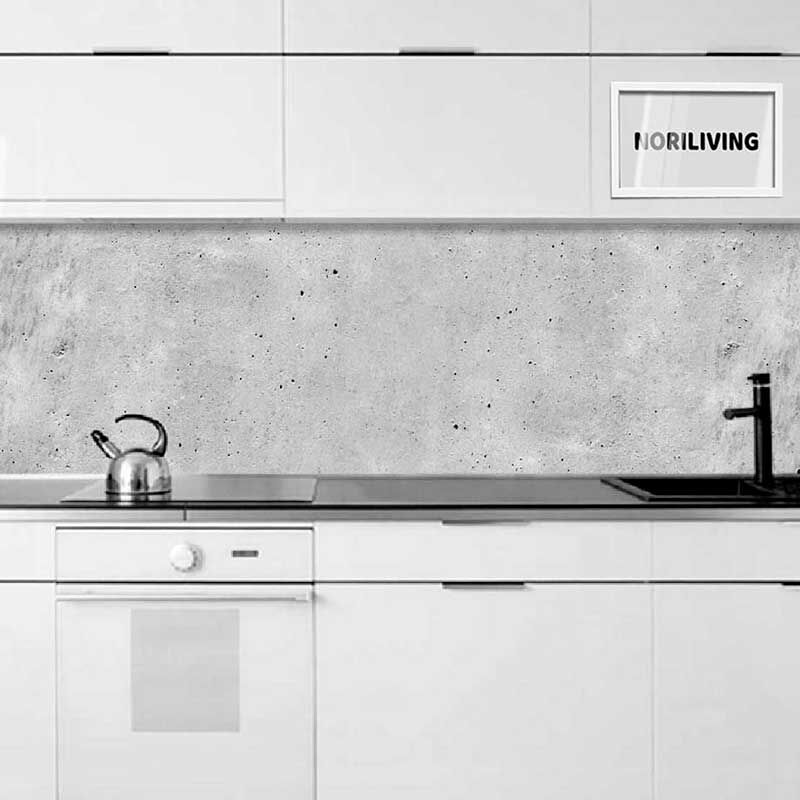 Moderne weiße Küche mit grauer Betonrückwand, Wasserkocher auf der Arbeitsfläche und schwarzem Wasserhahn. Oberschränke mit integriertem Schriftzug.