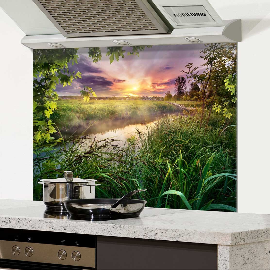 Moderne Küche mit Rückwandbild eines malerischen Sonnenuntergangs in der Natur, im Vordergrund Küchentöpfe und -pfannen auf der Arbeitsfläche