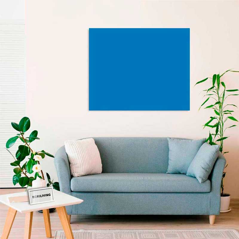 Ein modernes Wohnzimmer mit einer blauen Couch, Pflanzen und einem blauen Gemälde an der Wand.