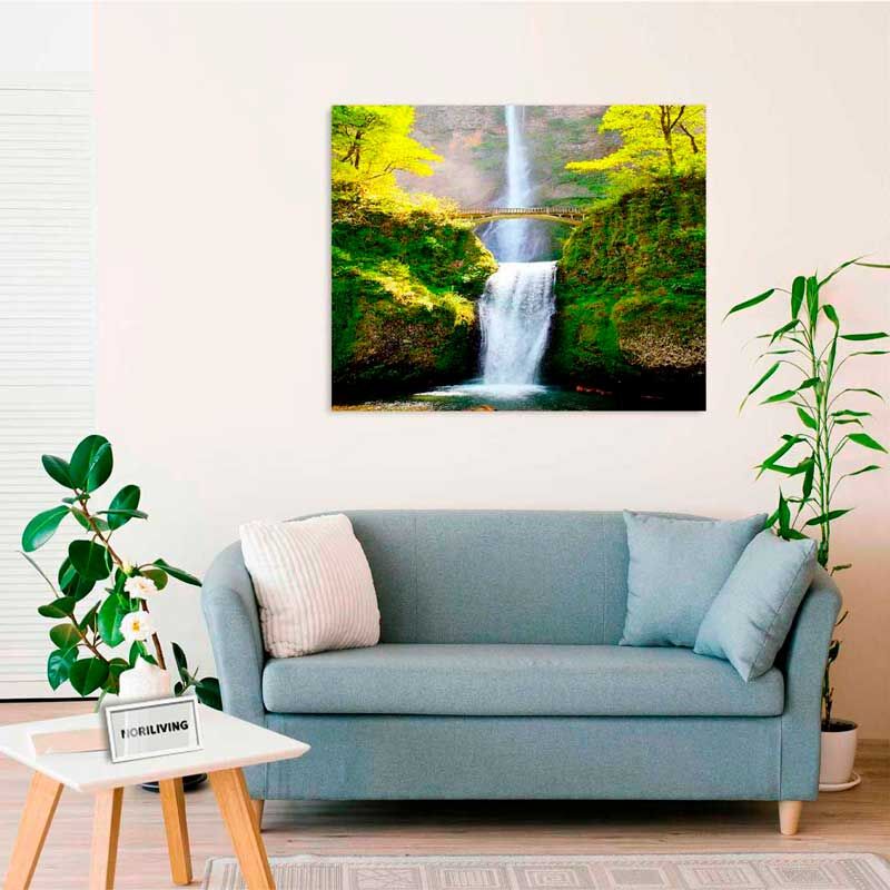 Ein stilvoll eingerichtetes Wohnzimmer mit einem Sofa, einem Beistelltisch und Pflanzen. Ein Leinwandbild eines Wasserfalls hängt an der Wand.