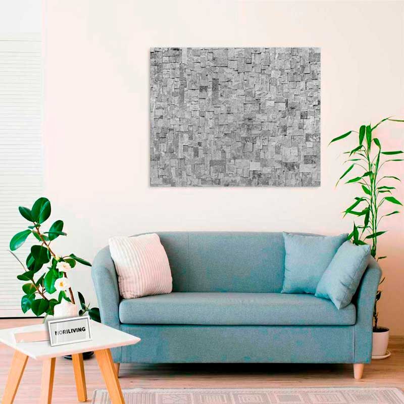 Ein modernes Wohnzimmer mit einem blauen Sofa, einem kleinen Tisch und einem grauen Kunstwerk an der Wand.