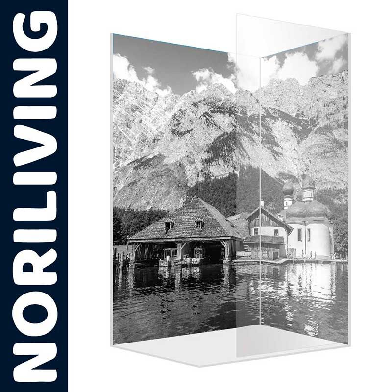 Schwarzweiß-Fotografie eines Bergsees mit traditionellem Haus und Kirche, eingerahmt von majestätischen Bergen. Glasbild von Noriliving.