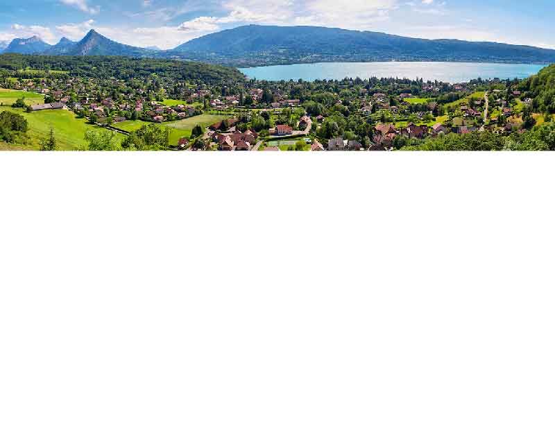 Landschaftsansicht des Annecy-Sees umgeben von Bergen und grünen Feldern in den französischen Alpen