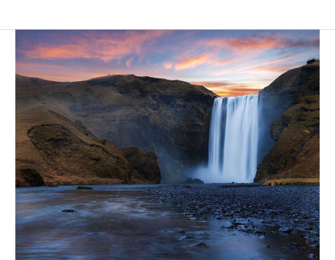 Ein imposanter Wasserfall stürzt inmitten einer felsigen Schlucht in die Tiefe, während der Himmel in warmen Farben des Sonnenuntergangs erstrahlt.