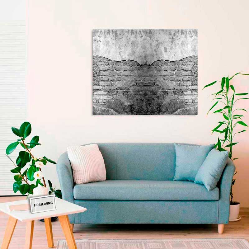 Ein Wohnzimmer mit einer blauen Couch, dekoriert mit einem großen, schwarz-weißen Wandkunstwerk aus Ziegelsteinmotiv an der Wand.
