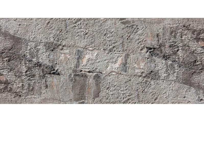 Nahaufnahme einer verwitterten Ziegelsteinwand, die Risse und Abnutzungen zeigt