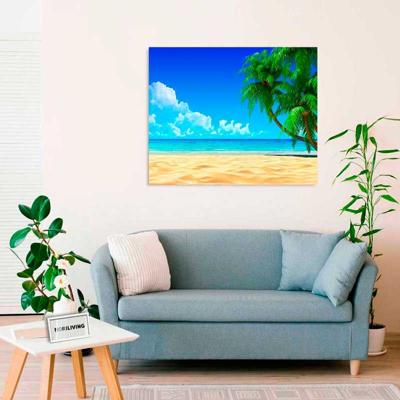 Ein Wohnzimmer mit einem blauen Sofa, zwei Pflanzen und einem Bild an der Wand, das einen Strand mit Palmen und blauem Himmel zeigt.