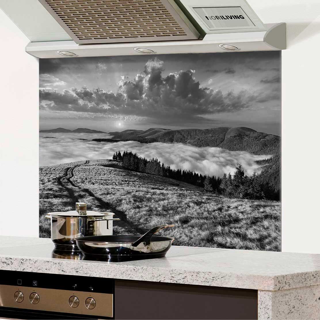 Moderne Kücheneinrichtung mit silbernen Töpfen auf einer Arbeitsfläche und einer beeindruckenden Küchenrückwand, die eine schwarzweiße Berglandschaft zeigt.