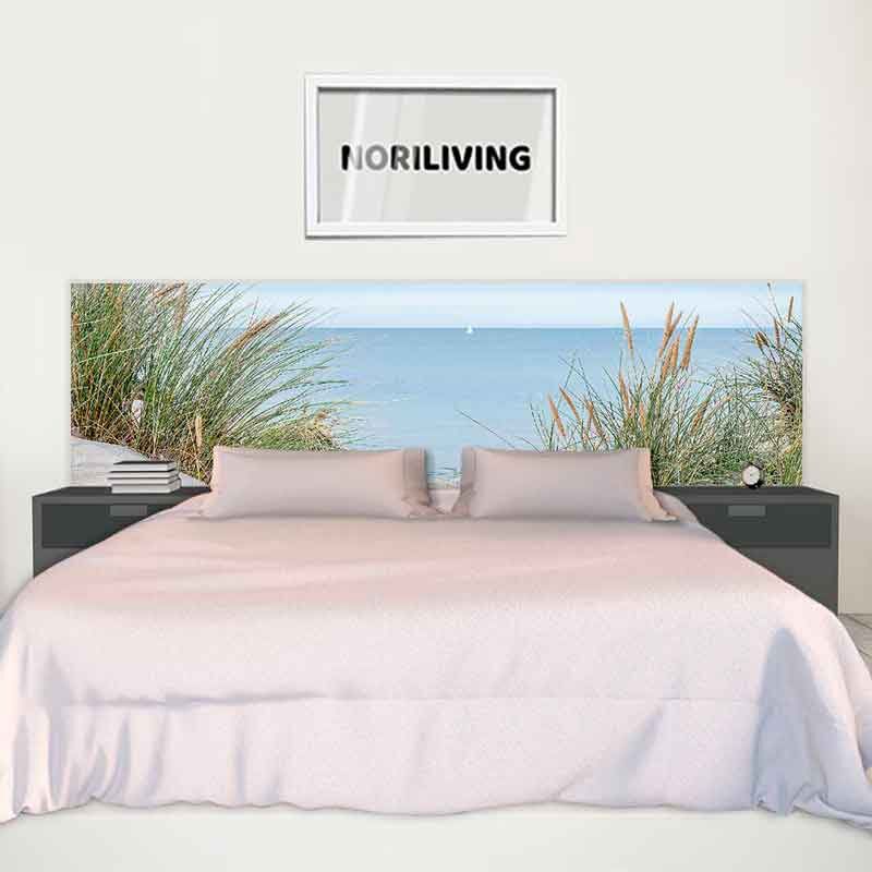 Schlafzimmer mit einem Bett, dessen Kopfteil ein Strandmotiv zeigt, und zwei Nachttischen mit einem NORILIVING-Bild darüber.