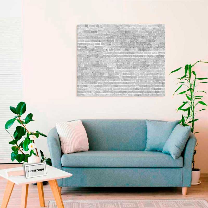 Ein gemütliches Wohnzimmer mit einer blauen Couch, Pflanzen und einem Wandbild aus grauen Ziegeln.
