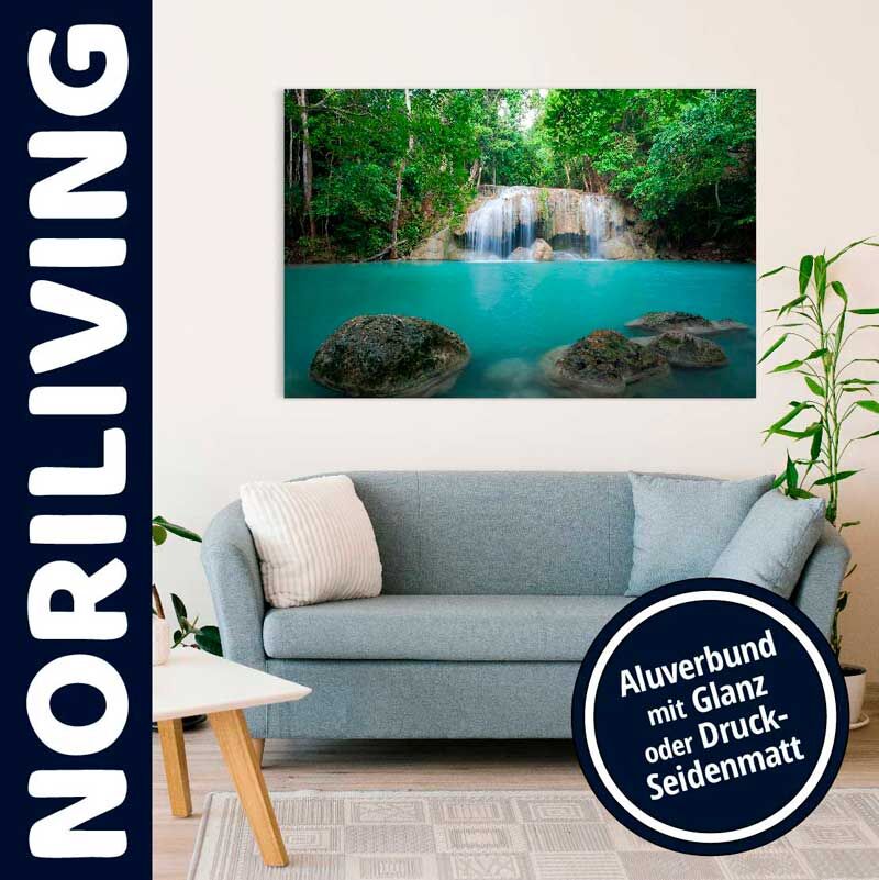 Wohnzimmer mit einem Noriliving Wandbild, das einen idyllischen Wasserfall über einem türkisfarbenen Teich zeigt, hängend über einem blauen Sofa
