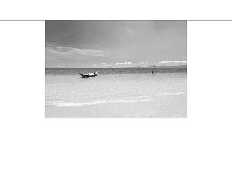 Ein verlassenes Boot im seichten Wasser an einem leeren, sonnigen Strand