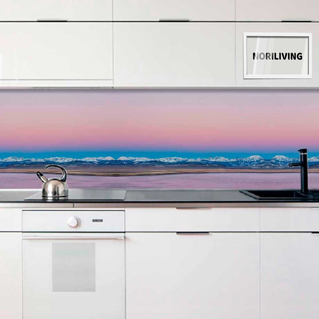 Küchenzeile mit weißem Schrank, eingebautem Herd, Wasserkocher und einer Rückwand mit Berglandschaft in Pastellfarben