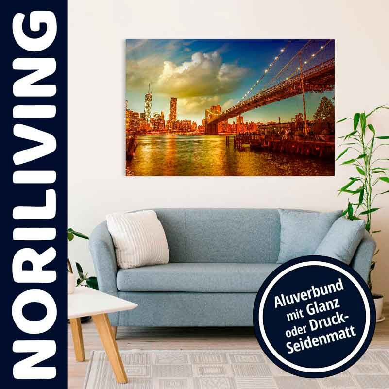 Wohnzimmer mit grauem Sofa und großem Wandbild einer beleuchteten Skyline mit Brücke, in Aluverbund mit Glanz oder Druck-Seidenmatt