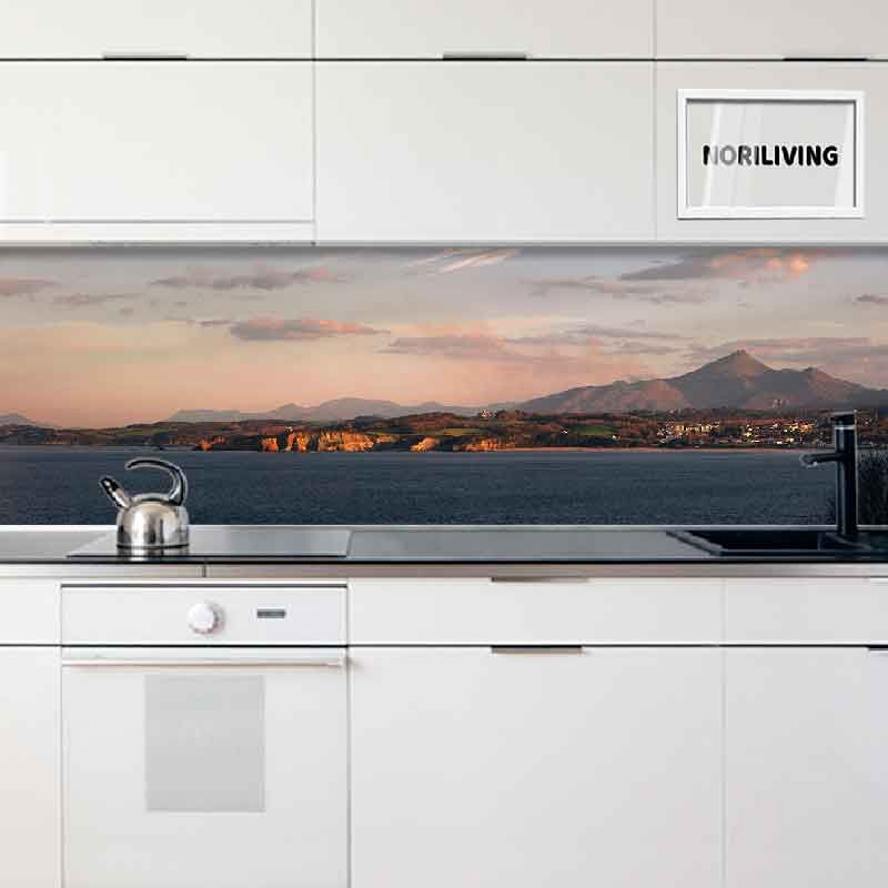 Helle Küche mit einer Rückwand, die eine malerische Landschaft darstellt, mit Bergen und Meer.