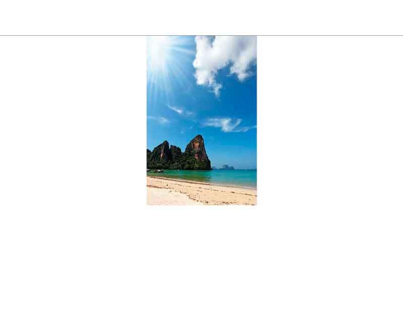Sonniger Strand mit klarem Himmel und Felsen im Hintergrund