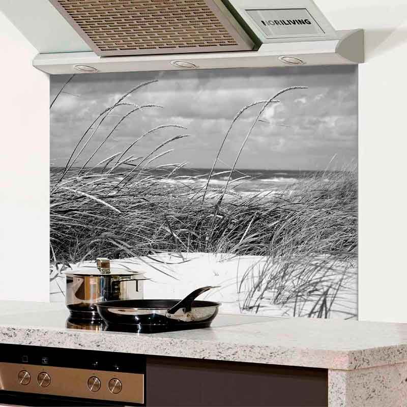 Dekorative Küchenrückwand mit einem Bild von Dünen und Meer in Schwarz-Weiß, im Vordergrund Kochutensilien auf der Arbeitsplatte