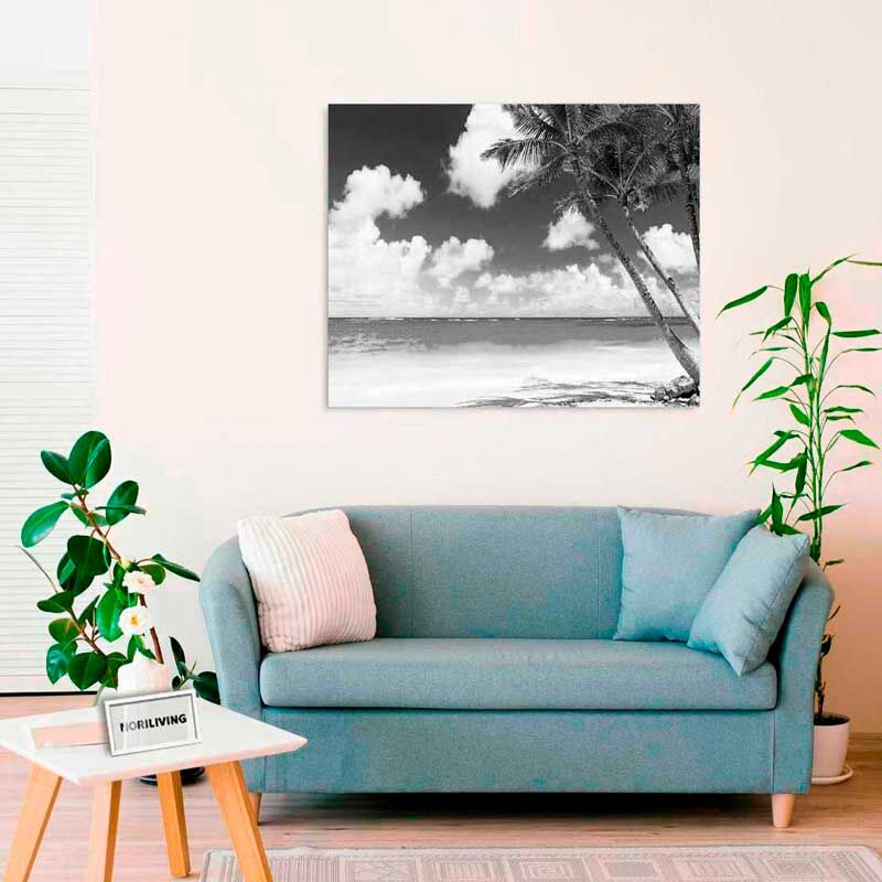 Ein stilvoll eingerichtetes Wohnzimmer mit einem blauen Sofa und einem Schwarz-Weiß-Strandbild an der Wand.