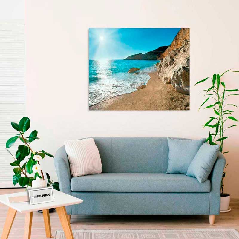 Ein gemütliches Wohnzimmer mit einem blauen Sofa, einem Couchtisch und einer Fotografie von einem Strand an der Wand.