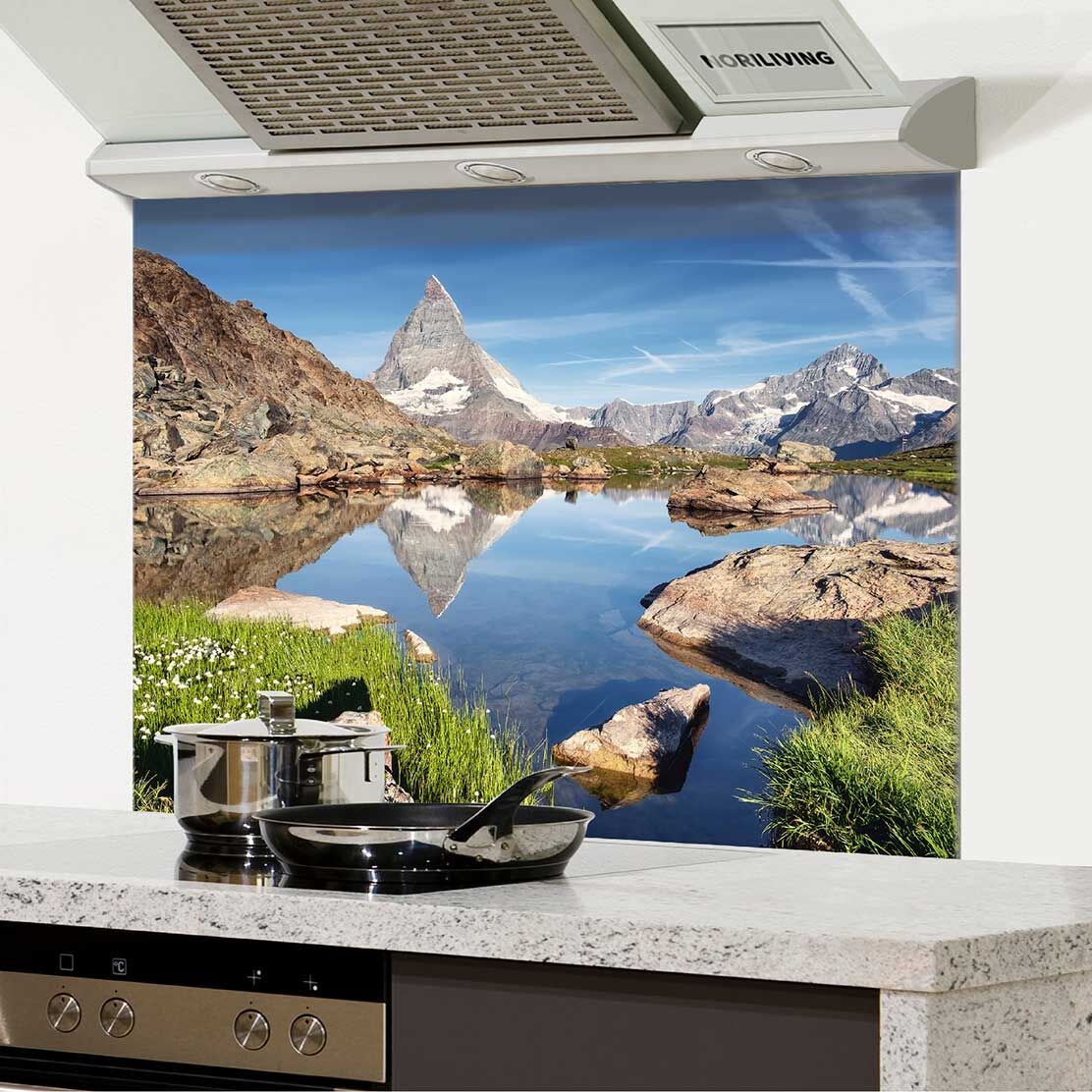 Hochwertiger Küchen-Spritzschutz mit beeindruckendem Matterhorn-Motiv und Landschaft, montiert über einem modernen Kochfeld.