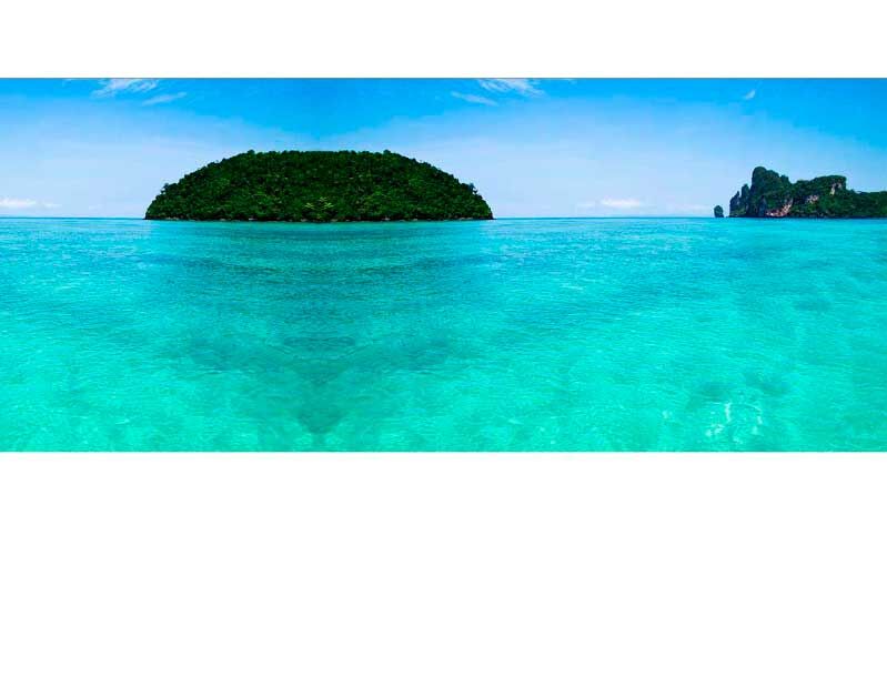 Blick auf eine grüne Insel umgeben von türkisfarbenem Meer unter einem klaren blauen Himmel