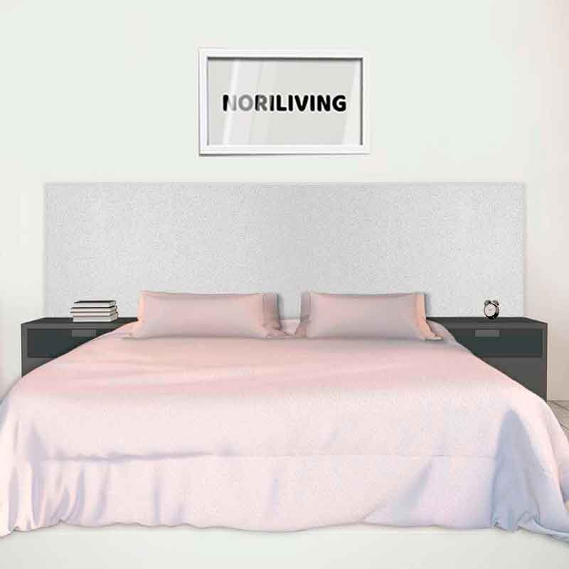 Ein modernes Schlafzimmer zeigt ein großes, weißes Doppelbett mit neutraler Bettwäsche und zwei schwarzen Nachttischen. Über dem Bett hängt ein gerahmtes Bild mit der Aufschrift 'NORILIVING'. Im Hintergrund ist eine helle Wand zu sehen.