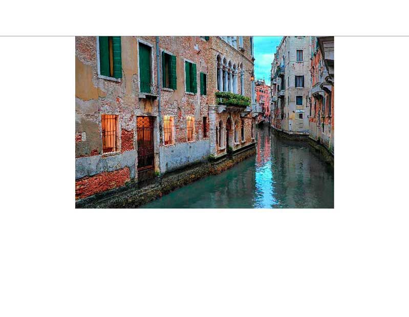 Idyllische Szene eines Kanals in Venedig, umgeben von historischen Gebäuden mit beleuchteten Fenstern bei Dämmerung