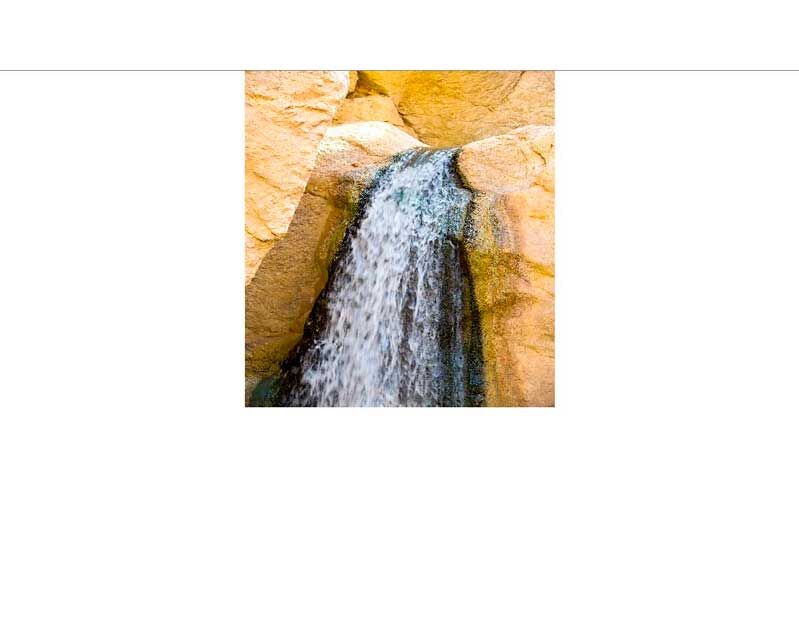Ein kleiner Wasserfall fließt über helle Felsen in einer natürlichen Umgebung.