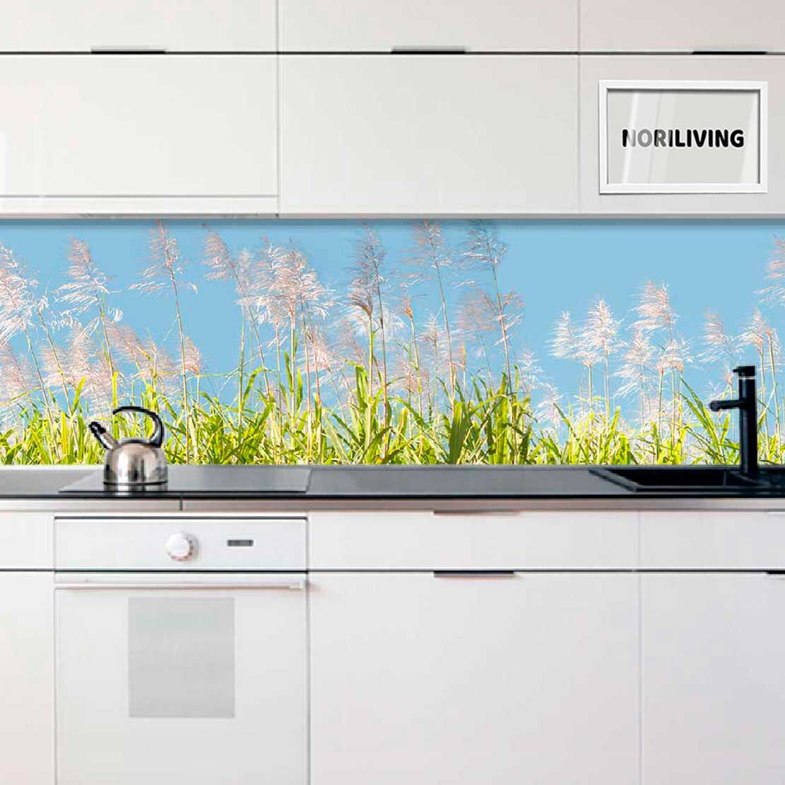 Küche mit weißem Design und einem Spritzschutz mit grünen Gräsern und blauem Himmel