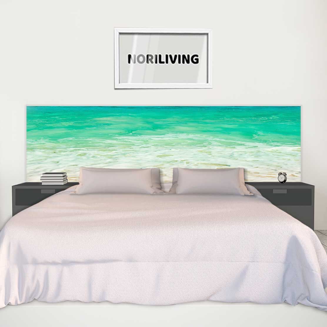 Ein stilvolles Schlafzimmer mit einem Bett, dessen Kopfteil mit einem tropischen Strandmotiv bedruckt ist, und einem Bild an der weißen Wand darüber.