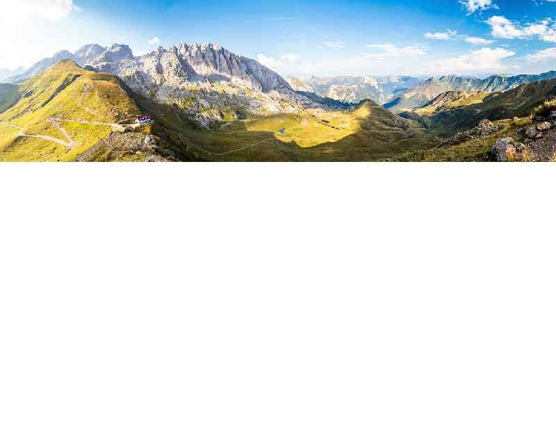 Landschaftspanorama mit Bergen und grünen Tälern unter blauem Himmel
