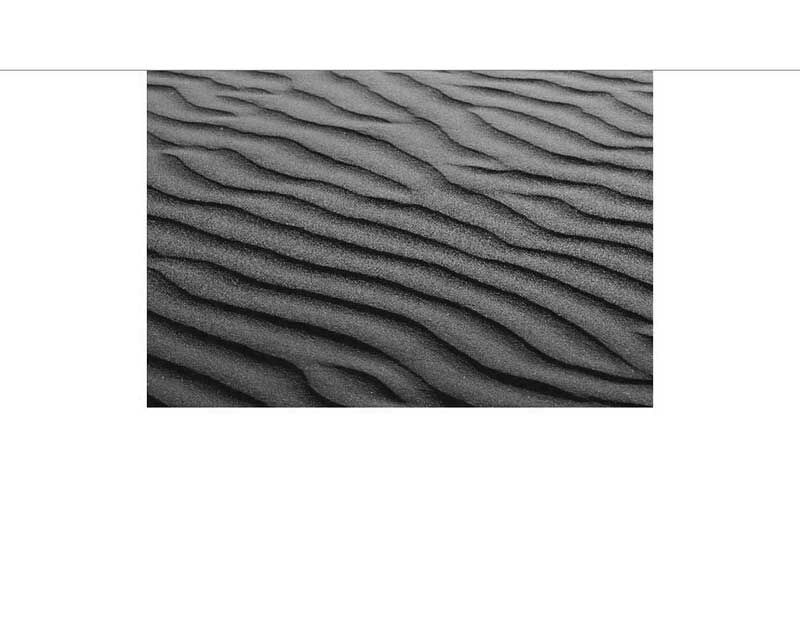 Schwarzweiß-Foto von Sanddünen mit erkennbarem wellenförmigem Muster.