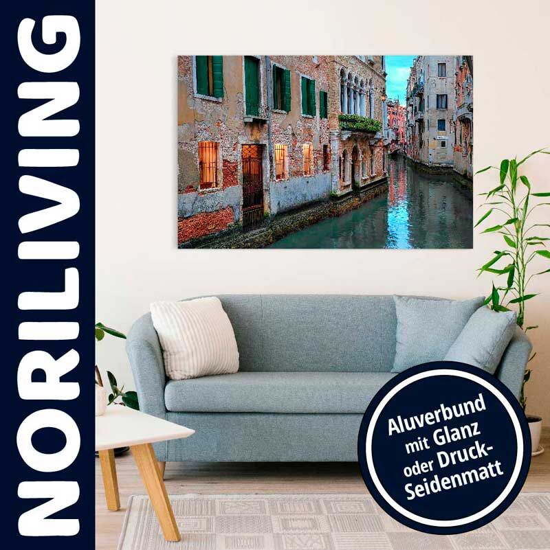 Ein Aluverbundbild mit venezianischem Kanalmotiv hängt über einem grauen Sofa in einem stilvoll eingerichteten Wohnzimmer.