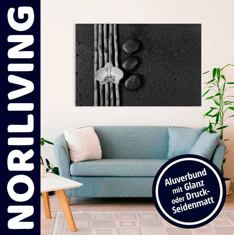 Wohnzimmer mit blauem Sofa und Aluverbund-Wandbild von Noriliving, mit Bambusstäben, Steinen und Blume dargestellt. Perfekte Ergänzung für stilvolle Inneneinrichtung.
