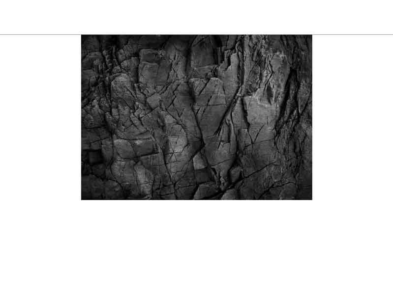 Schwarz-weiße Texturansicht einer rauen, rissigen Felswand