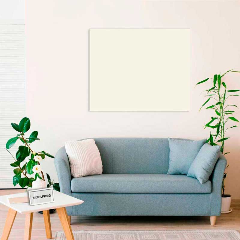 Helles Wohnzimmer mit blauem Sofa, Kissen, weißem Couchtisch, Zimmerpflanzen und leerer Leinwand an der Wand