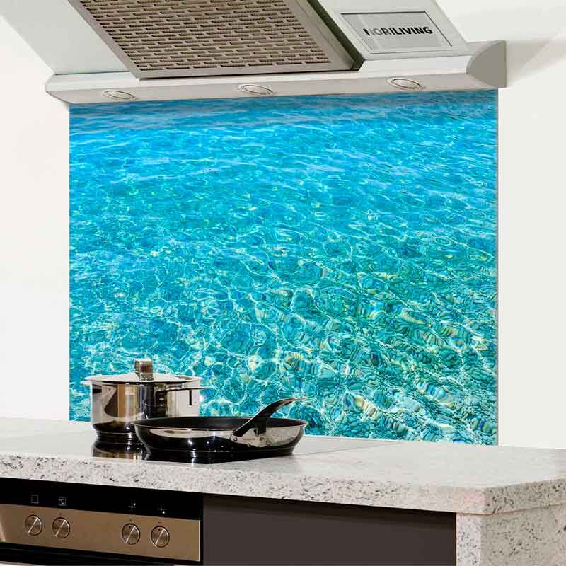Modern gestaltete Küche mit Glasrückwand, die ein realistisches Wasser-Motiv zeigt, ergänzt durch Dunstabzugshaube und kochendes Geschirr auf der Arbeitsplatte.
