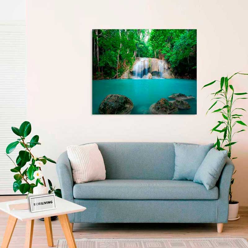 Modernes Wohnzimmer mit einem blauen Sofa, Pflanzen und einem Wandbild mit einem Wasserfall.