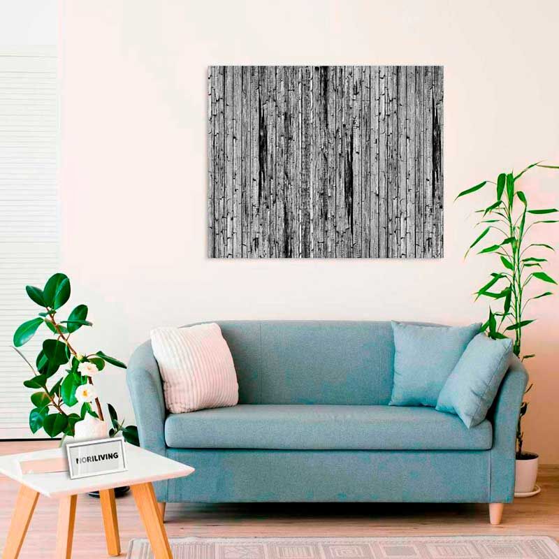 Ein stilvolles Wohnzimmer mit einer blauen Couch, dekoriert mit Kissen, und einer großen Leinwand mit Holzmotiv an der Wand. Pflanzen stehen um die Couch herum.