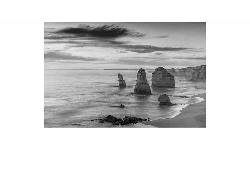 Schwarzweiß-Aufnahme der Felsformation Twelve Apostles an der australischen Küste, umgeben von Meer und Himmel