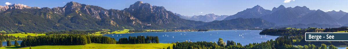 Panorama einer Berglandschaft mit See und Segelbooten Idyllische Berglandschaft mit einem See und Segelbooten im Vordergrund