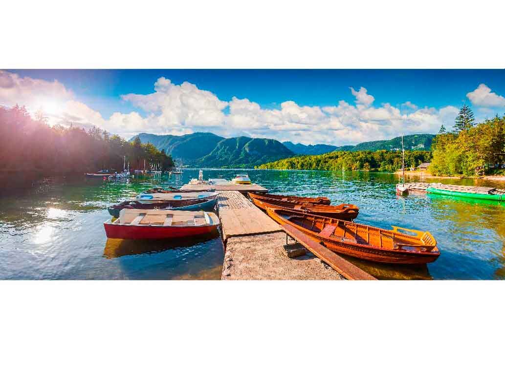 Boote an einer Anlegestelle auf einem ruhigen See mit Bergen im Hintergrund bei sonnigem Wetter