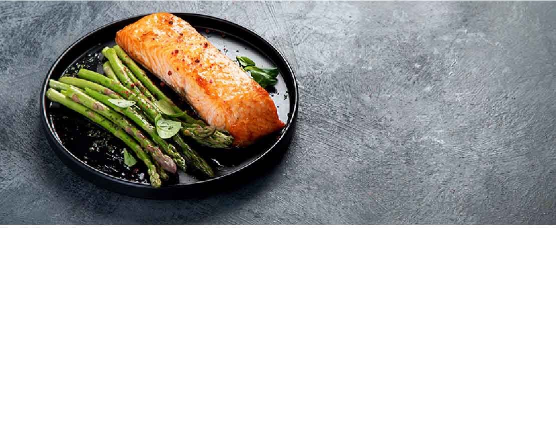 Ein Teller mit gegrilltem Lachs und Spargel auf dunklem Hintergrund