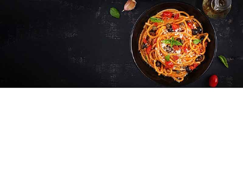 Ein Teller Spaghetti mit Tomatensauce, Oliven und frischen Kräutern auf schwarzem Hintergrund